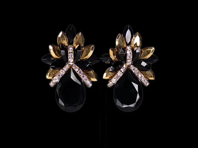 Close-up of black and gold crystal flower button earrings on a black background
