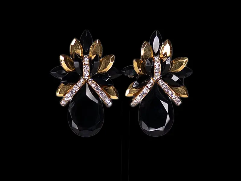 Close-up of black and gold crystal flower button earrings on a black background
